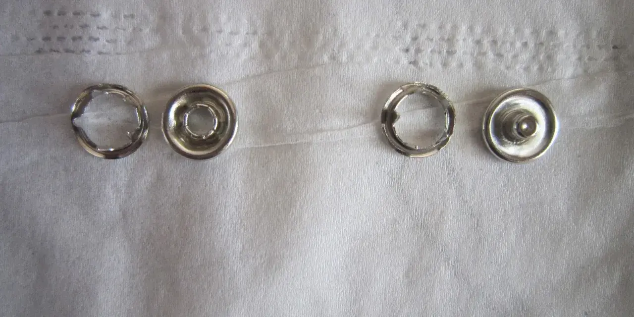 Quatre pièces de bouton pression métal argenté, prêtes à poser sans pince.