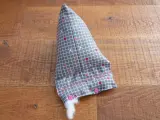 Un berlingot tissu gris à petits cœurs roses et blancs, en cours de rembourrage, est posé sur un parquet en bois.