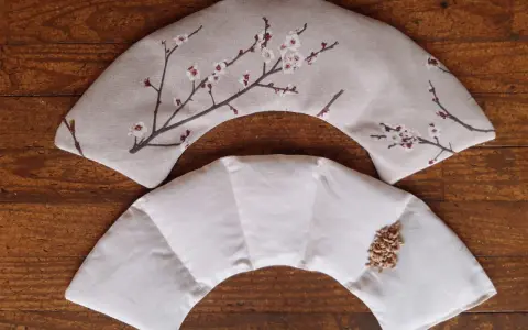 Tuto bouillotte sèche cervicale : deux coussins en tissu, l'un décoré de fleurs de cerisier, l'autre prêt à être rempli de grains.