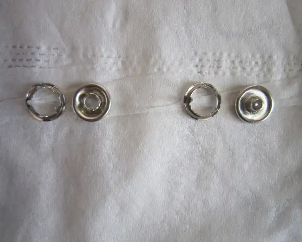 Quatre pièces de bouton pression métal argenté, prêtes à poser sans pince.