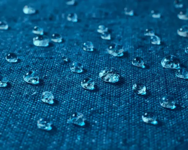 Gouttes d'eau perlant sur un tissu bleu, illustrant comment imperméabiliser un tissu naturellement.