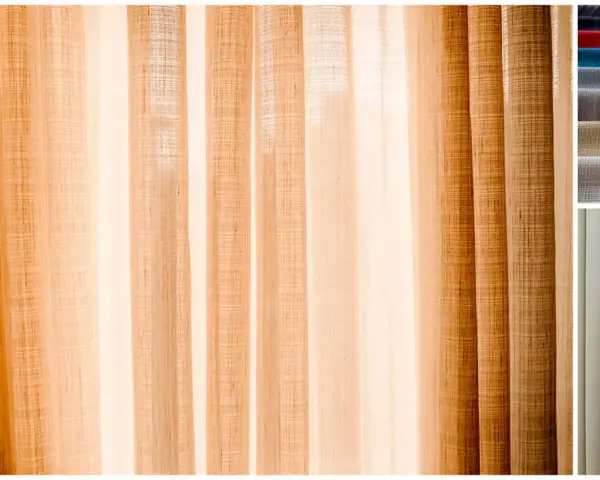 Drapés de lin aux tons chauds, parfaits pour coudre un rideau. Échantillons de tissus et pompon décoratif.