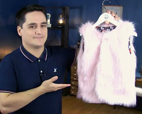 Un homme présente un adorable gilet berger bébé en fausse fourrure rose. Un patron gratuit pour le coudre est disponible.
