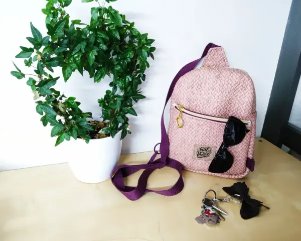 Sac à dos rose texturé, parfait pour une femme. Un patron sac à dos femme gratuit pour créer le vôtre. Lunettes de soleil et clés à proximité.
