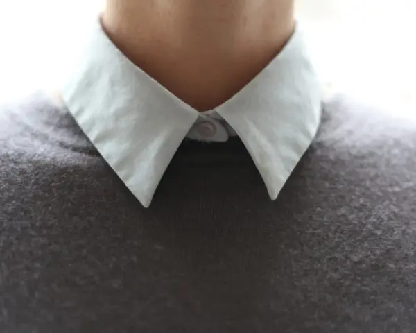 Gros plan sur un col froncé blanc sur un pull gris.