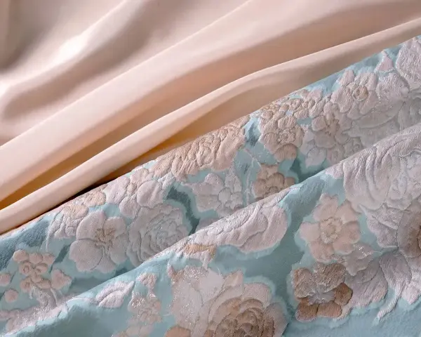 Tissu texturé bleu ciel avec des motifs floraux et un tissu satiné pêche. Parfait pour une robe d'été élégante.