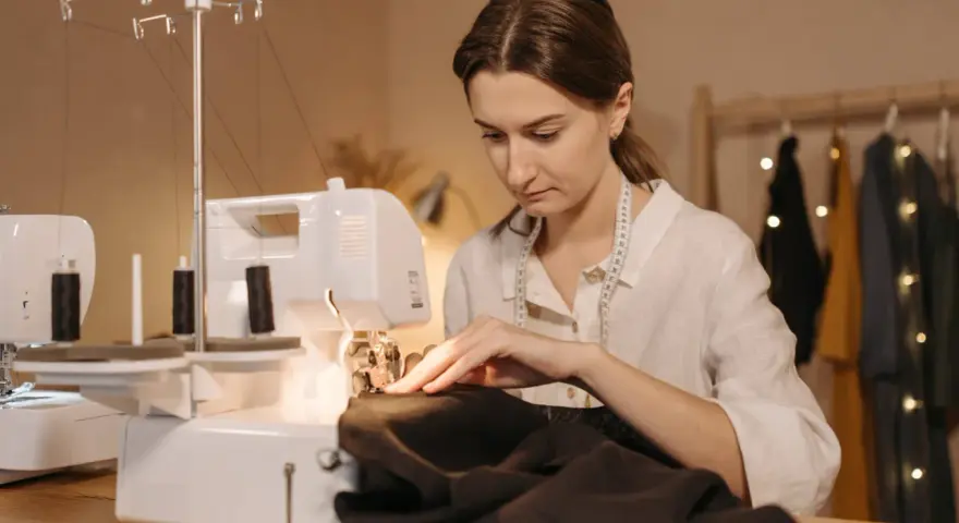 Une couturière utilise une surjeteuse pour créer un patron housse de chaise Burda.