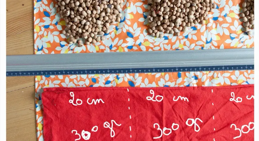 Préparation d'une bouillotte aux noyaux de cerise. Quel tissu choisir ? Ici, un coton imprimé et un tissu rouge marqué pour la découpe.