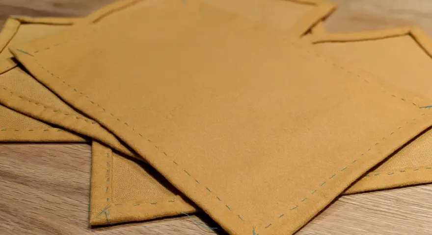 Serviettes de table en tissu ocre, finitions soignées. Idéal pour un tuto serviette de table facile à réaliser.