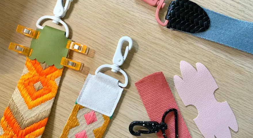Tuto sangle : plusieurs anses de sacs colorées, avec mousquetons et pièces en cuir, prêtes à être assemblées.