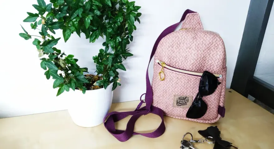 Sac à dos rose texturé, parfait pour une femme. Un patron sac à dos femme gratuit pour créer le vôtre. Lunettes de soleil et clés à proximité.