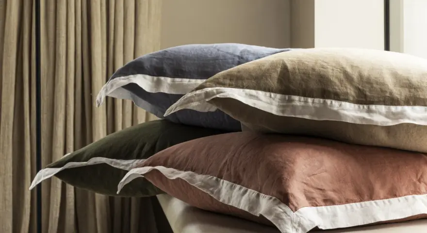 Pile de coussins aux couleurs douces, bleu, kaki, ocre, avec bordure blanche. Le percale de coton, c'est quoi ? Une matière douce et respirante.