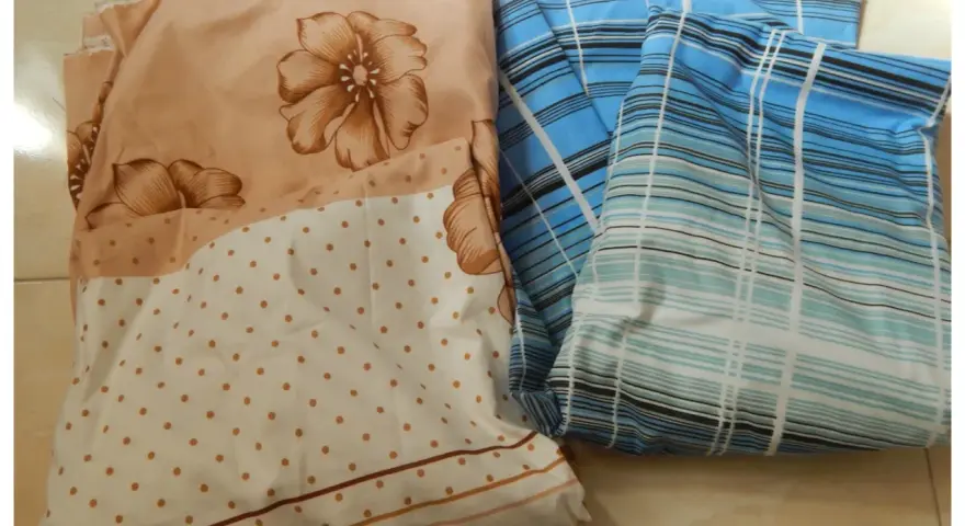 Tissus pliés, un à fleurs beiges et pois, l'autre à rayures bleues. Idéal pour apprendre comment faire un drap housse.
