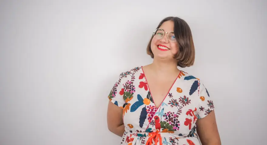 Une femme souriante porte une robe d'été colorée, un modèle inspiré d'un patron gratuit de robe Charlotte.