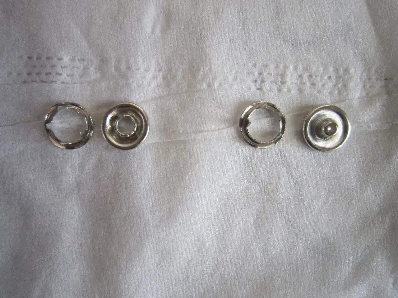 Quatre pi&egrave;ces de bouton pression m&eacute;tal, pr&ecirc;tes &agrave; poser sans pince.