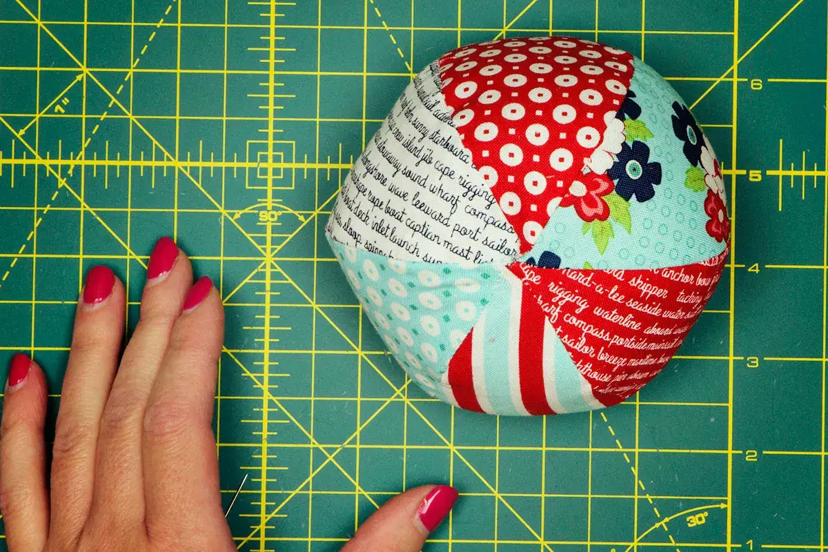 Balle en tissu aux motifs marins, id&eacute;ale pour un patron gratuit balle en tissu. Une main aux ongles vernis rose vif est pos&eacute;e &agrave; c&ocirc;t&eacute;.