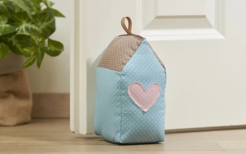 Un cale porte en tissu gratuit en forme de maison, avec un cœur rose. Parfait pour un **patron cale porte en tissu gratuit**.